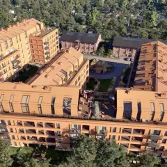 Nowoczesne budynki mieszkalne nawiązujące architekturą do historycznego folwarku Scheiblera. Widać ceglane elewacje, spadziste dachy i zielone dziedzińce.