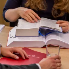 Dwie osoby analizują przepisy prawne dotyczące najmu i przedawnienia. Na stole dokumenty, książki i szklanka wody.