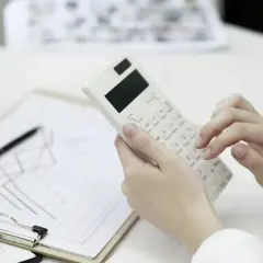 Ręce liczą na kalkulatorze, analizując wykresy. Warto sprawdzić, jak kredyt a inflacja wpływają na finanse.