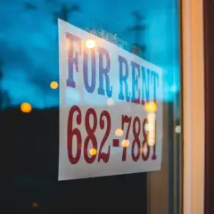 Szyba z napisem "FOR RENT" i numerem telefonu. Czy to dzierżawa, czy najem? Zadzwoń i się dowiedz!
