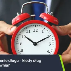 Dłoń trzyma czerwony budzik. Tekst: "Przedawnienie długu – kiedy dług się przedawnia?". Dotyczy to również czynszu najmu.