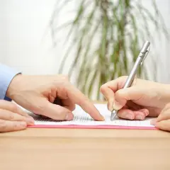 Dłoń wskazuje na tekst, druga podpisuje umowę poręczenia.