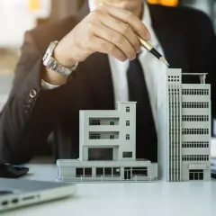 Biznesmen analizuje modele budynków, rozważając umowę na rok i możliwość jej wypowiedzenia.