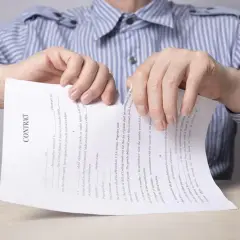 Ręce drą umowę. Bank wypowiedział umowę kredytu, co symbolizuje podarcie dokumentu.