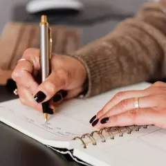 Kobieta pisze w notatniku, planując, jak znaleźć poręczyciela.