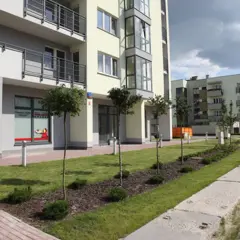 Nowoczesne budynki mieszkalne w stylu neowo bemowo z zielonymi skwerami i chodnikiem.