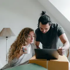 Para omawia na laptopie, co z kredytem po śmierci. Kobieta trzyma kubek, mężczyzna wskazuje na ekran.