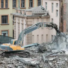Koparka niszczy budynek do rozbiórki. Co z lokatorami? Gruz i pył unoszą się w powietrzu.