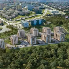 Nowe inwestycje w Kielcach: nowoczesne bloki mieszkalne otoczone zielenią, w tle widoczne osiedla i droga.