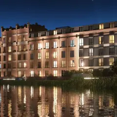 Nowoczesny **młyn nad Cybiną** w nocnej scenerii. Ceglana fasada, liczne okna z ciepłym światłem, odbijające się w spokojnej wodzie.