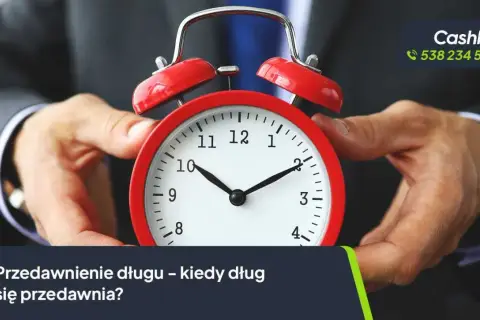Dłoń trzyma czerwony budzik. Tekst: "Przedawnienie długu – kiedy dług się przedawnia?". Dotyczy to również czynszu najmu.