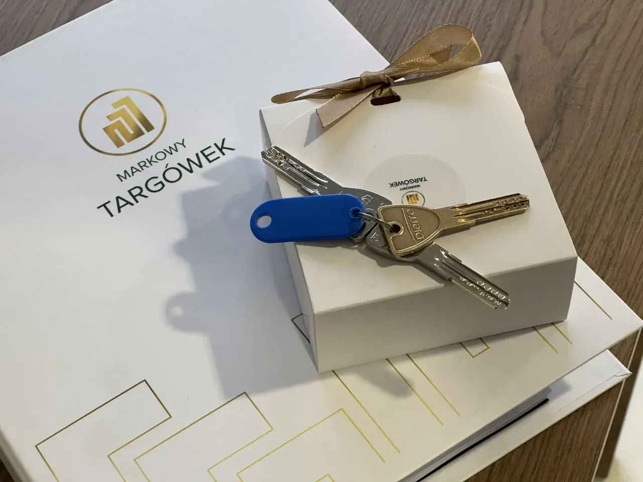 Klucze do nowego mieszkania na Markowym Targówku, zapakowane w eleganckie pudełko z logo.