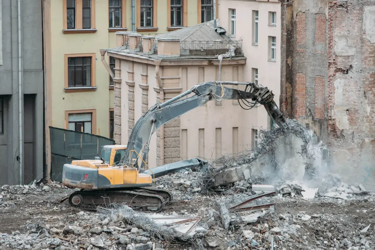 Koparka niszczy budynek do rozbiórki. Co z lokatorami? Gruz i pył unoszą się w powietrzu.