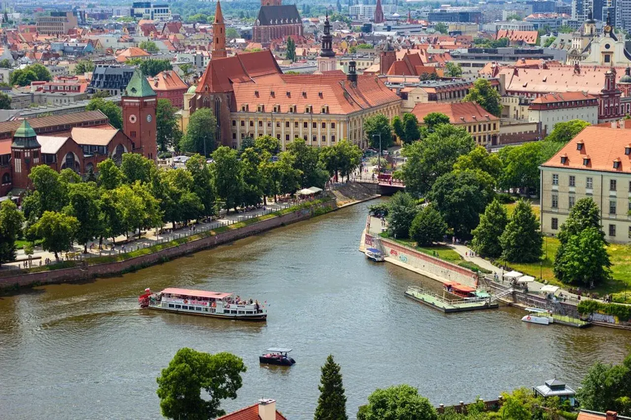 Wrocław inwestycje: malowniczy widok na Odrę z zabytkową architekturą i statkami wycieczkowymi.