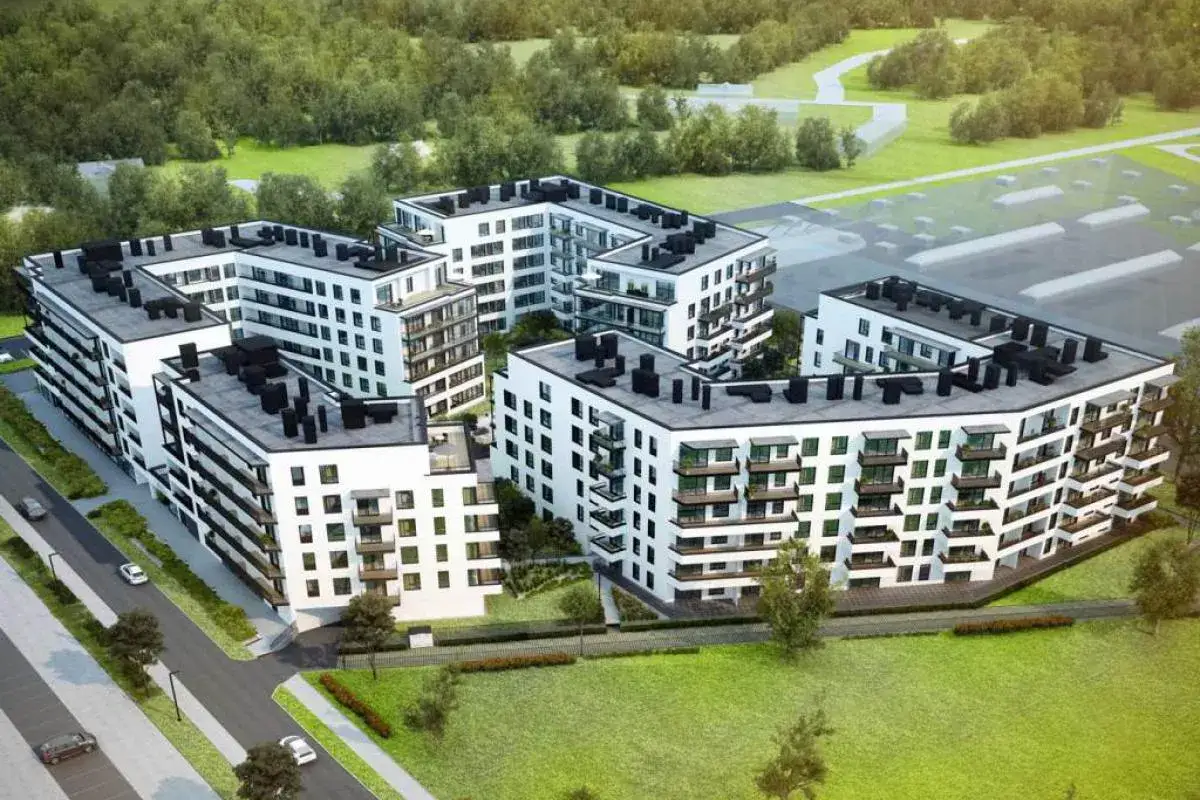Nowoczesne osiedle przy alejach, z białymi budynkami o geometrycznych kształtach, otoczone zielenią.