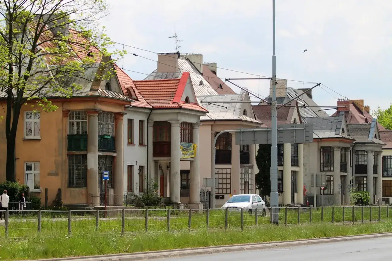 Rząd kamienic w stylu historyzmu, dawne osiedle oficerskie Kraków. Charakterystyczne kolumnowe portyki i czerwone dachy.