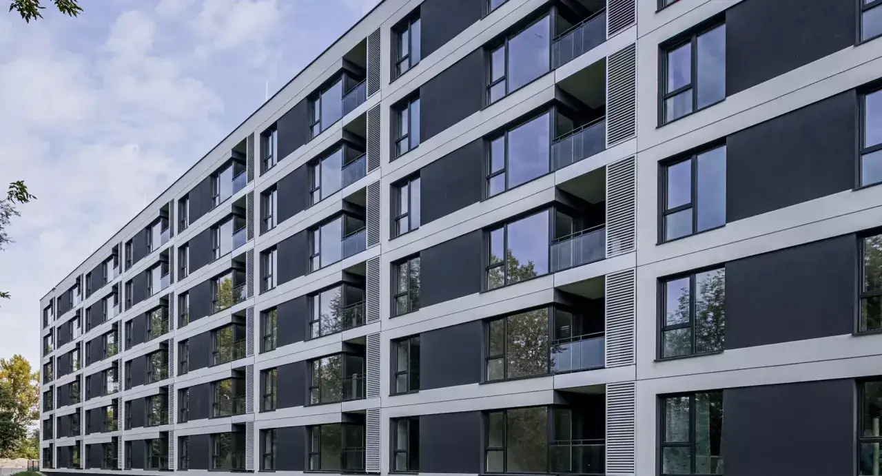 Nowoczesny budynek mieszkalny z balkonami i dużymi oknami. Elewacja w odcieniach szarości i czerni. To dzieło sztuki architektonicznej, jakby z art. 664 kc.